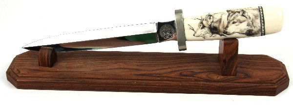 KNIFE WITH SCRIMSHAW HANDLE: Scrimshaw handle signed Andhi. Overall length 12 inches. Comes with stand.