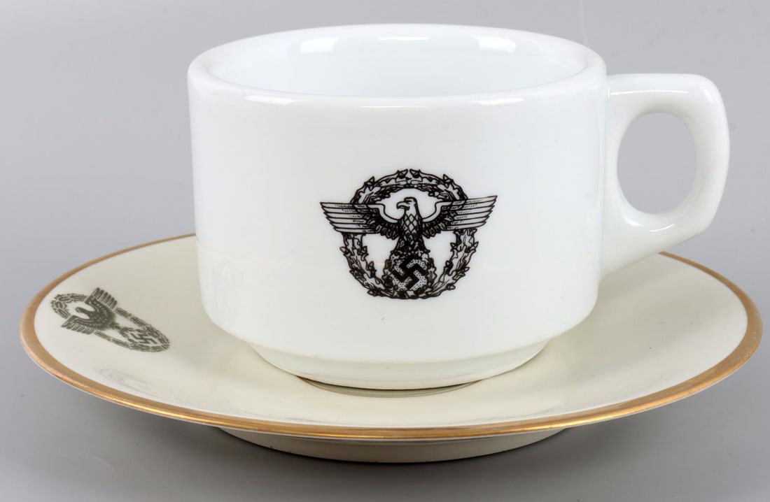 WWII GERMAN REICH POLIZEI ORPO COFFEE CUP & SAUCER: Lot of two (2) WWII German Reich Polizei Orpo(Ordnungspolizei) porcelain dinnerware including a coffee mug and a saucer. Both items feature the order police eagle and wreath insignia. Cup's underside 