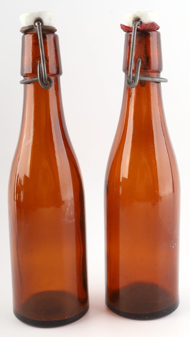 2 WWII GERMAN SS REICH & WAFFEN SS BEER BOTTLES: Lot of two (2) WWII German Reich beer bottles including an SS-Reich beer bottle, lid dated 1940, and a Waffen-SS beer bottle. Both bottles are approx. 9 1/2 inches tall. Both are in good condition.