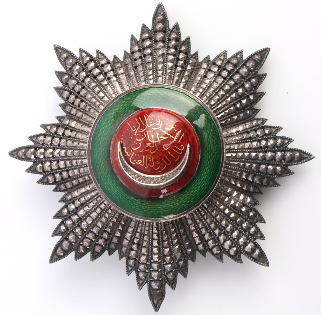 WWI TURKISH OTTOMAN EMPIRE ORDER OF OSMANIEH BADGE: WWI Ottoman Empire Order of Osmanieh (Osmanli) 1st class badge. Gilt silver with diamond like designs to the rays. Center piece of green and red enamel with the crescent moon and Arabic script. Arabic