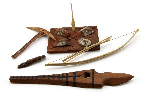 ALASKAN NATIVE AMERICAN ARTIFACTS MAMMOTH IVORY: Group of Alaskan Indian artifacts. Miniature bone bow and arrows (7.75 inches), mammoth ivory pick-axe-like tool (3.5 by 3.5 inches), carved horn pendant (2.1 inches), small wooded panel with four mas