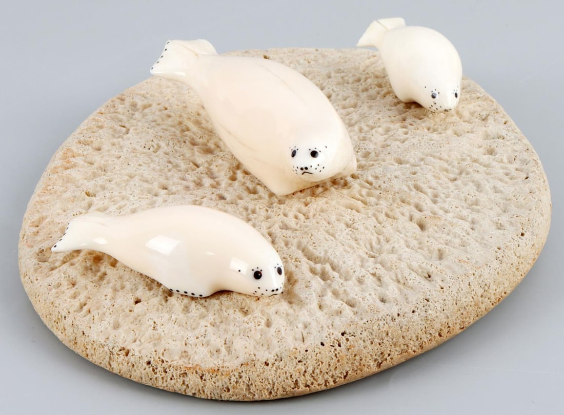 CHARLIE OLANNA INUIT ARTIST WALRUS TUSK SEAL ART: Signed bottom, measures 7 X 5 1/2 inches, walrus tusk seals and bone platform. No international sales, know your state law prior to bidding. This lot has a reserve.