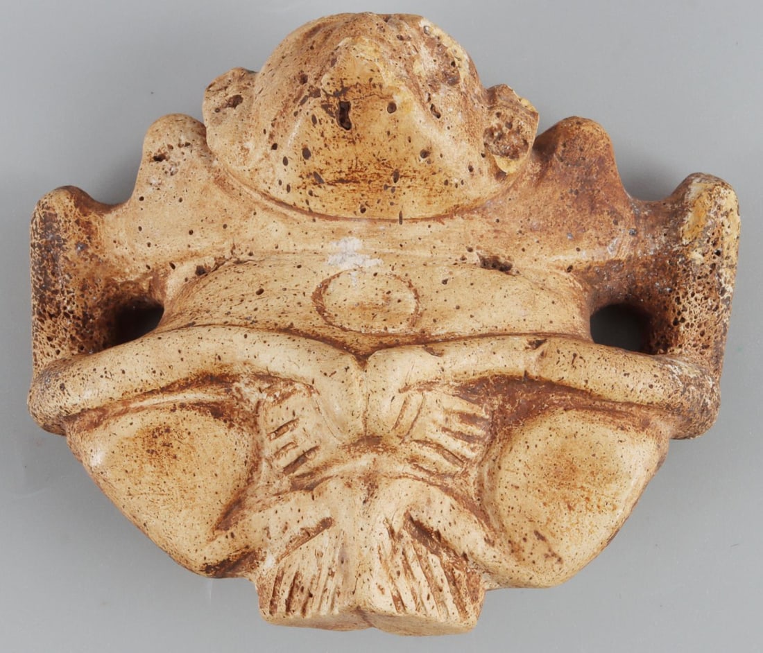 TAINO BAT MAN OR SHAMAN EFFIGY MANATEE BONE CARVED: Taino. PreColumbian. Anthropo-zoomorphic bat man or shaman effigy. Well separated shoulders support extended arms with hands resting on lower chest. The back exhibits a number if incised lines represe