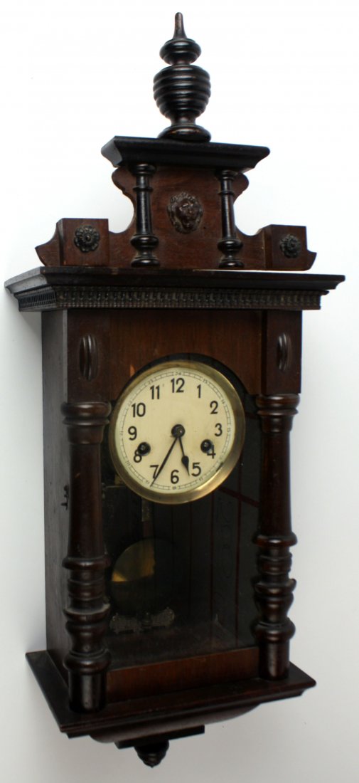 EARLY 20TH CENTURY WOODEN WALL CLOCK: Wooden boxed wall clock with glass front. 27 by 10 by 6 inches. No makers mark. Some wear to the varnish, and veneer. In apparent working condition, will need repair and tuning. Overall in very good c