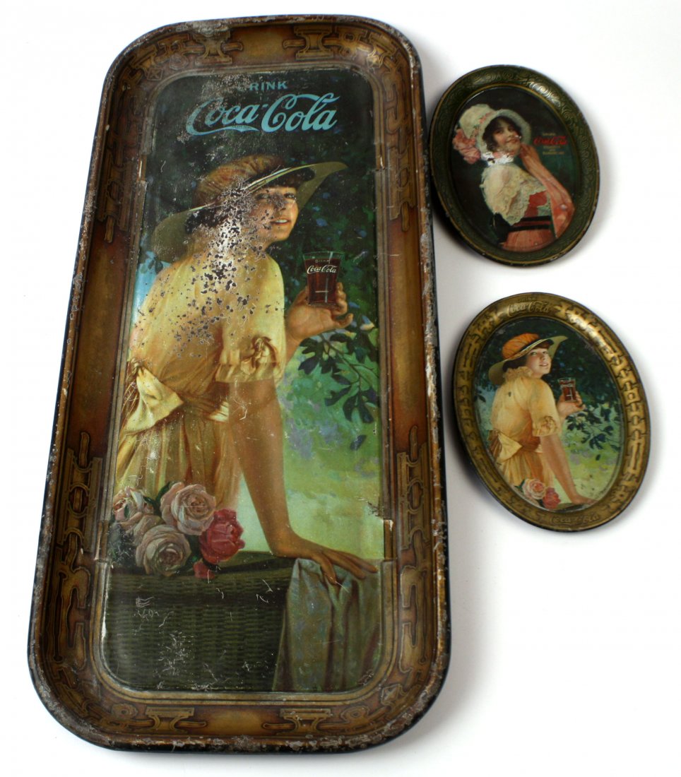 THREE 1916 COCA-COLA COKE TRAYS ELAINE & BETY: 1916 Elaine Coca-Cola Serving Tray (8.5 by 19 inches). Finish is heavily worn, has loss to printing around the face, the top logo, and the edges. The reverse also has wear and oxidation, in fair to go