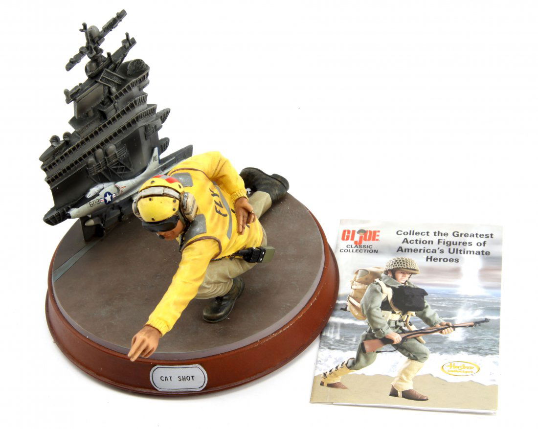 GI JOE LIMITED EDITION STATUE CAT SHOT 1/3673: Statue of aircraft carrier deck crewman shooter. Numbered 1/3673. Base measures 6 inches in diameter 9.25 inches high by 8.5 inches across. Includes original box and inserts. No chips or cracks, wood