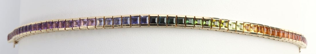 14KT GOLD AND MULTI COLOR GEMSTONE TENNIS BRACELET: Stamped and acid tested 14kt yellow gold with 565 approx 2.5mm emerald cut gemstones set in the colors arrangement of a rainbow. Length 7 inches. Total weight 19 grams This lot has a reserve.