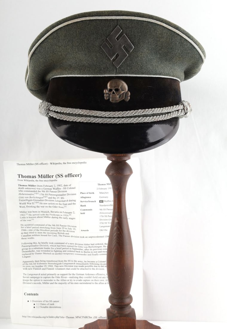 WWII GERMAN THIRD REICH THOMAS MULLER SS VISOR: Swastika pin and totenkopf pin featured in front. Silver piping around brim. Hat is size 56. Very good condition. GRUPPE WEST WASSERDICHT STIRNDRUCKFREI MAKE.