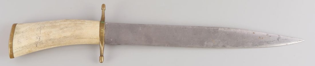 ANTIQUE DROP POINT FIGHTING KNIFE WITH BONE HANDLE: Unmarked 11 1/4 inches, total length 16 1/4 inches, brass double hilt and butt plate. Handle is bone with faded scrimshawed eagle.