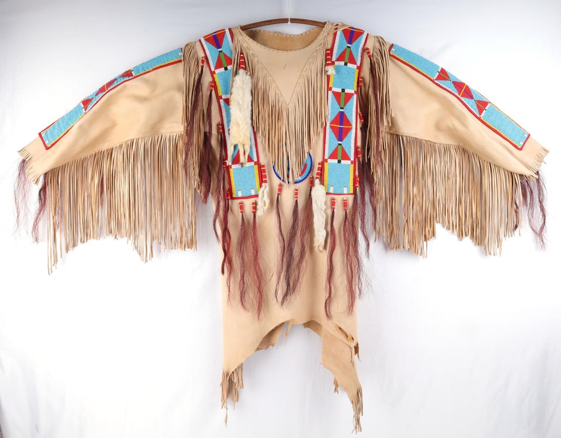 SIOUX INDIAN BEADED TANNED LEATHER WAR SHIRT: Brain tanned leather war shirt in very good condition. Tight beadwork, some use wear discoloring, ermine and horsehair ornamentation. Measurements: chest 35 inches, shoulders 36, Length 40 inches.