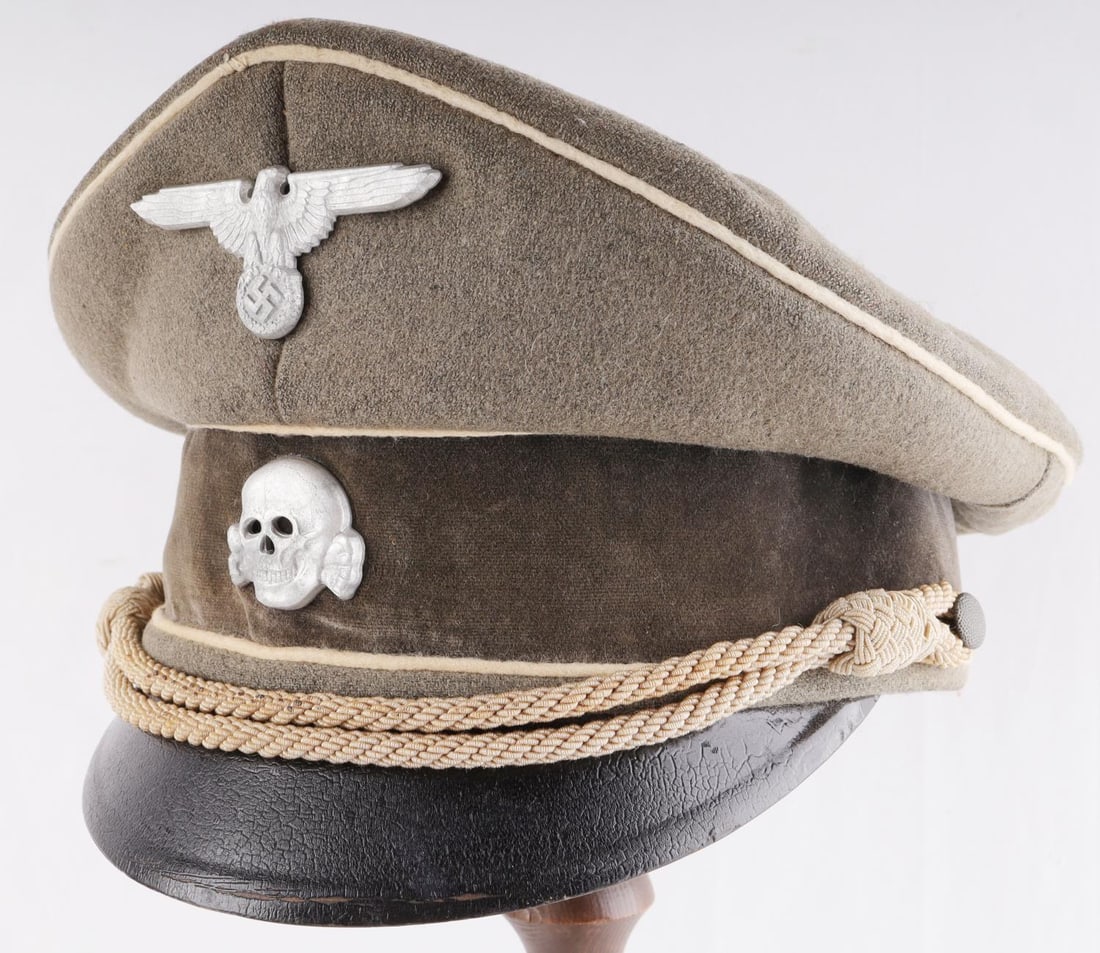 WWII GERMAN THIRD REICH WAFFEN SS VISOR CAP: SS visor officer cap with zinc Parteiadler and totenkopf. Piping is white and chin strap is bullion cord. Age featured throughout. Very good condition. Size 58. Likely post-war constructed.