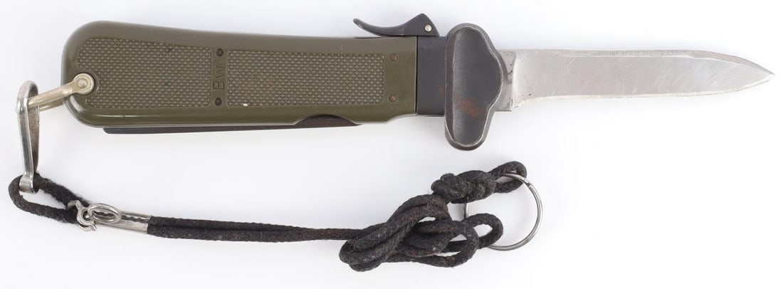 WWII GERMAN ARMY PARATROOPER GRAVITY KNIFE: German Army Paratrooper Knife from WMF features a spear point satin finish gravity blade. The handle is comprised of a steel guard and lever with OD Green plastic scales over metal frame. D Ring lanya
