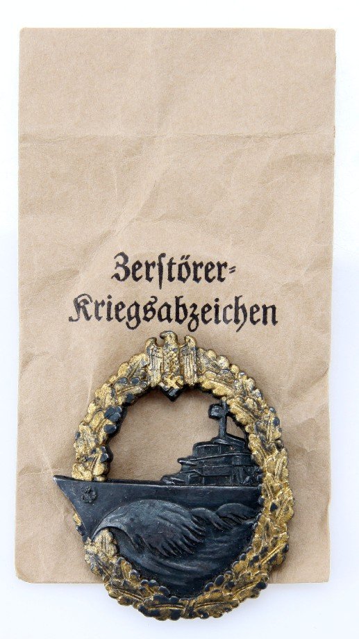 WWII GERMAN KRIEGSMARINE DESTROYER SERVICE BADGE: WWII German Kriegsmarine destroyer service badge, in original issue paper envelope. Alloy construction, with gilded oak wreath. Marked "LQ" on back, with coke bottle pin back. Very good condition.