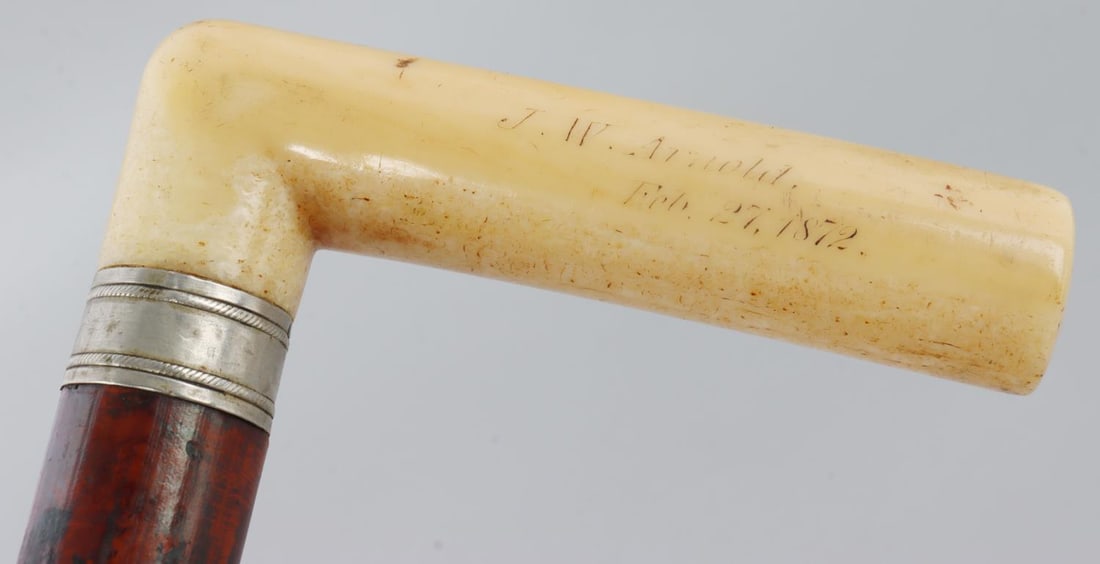 1872 DATED WALRUS TUSK GRIP WALKING STICK CANE: Some finish loss to shaft, grip named J.W. Arnold 1872, nice grip with metal wrap. Over 100 years old, no international sales, know your state laws prior to bidding. Measures 35 1/2 inches.