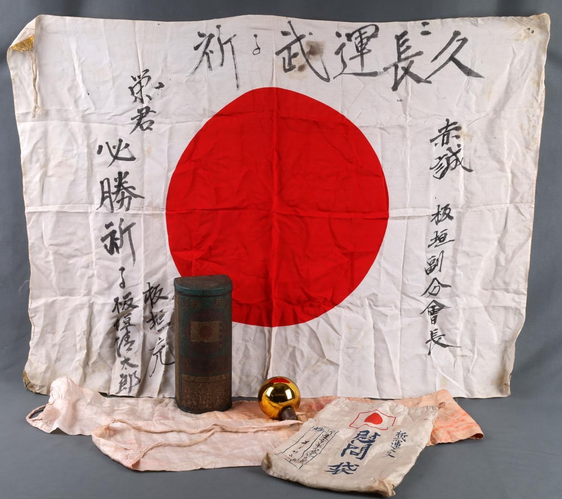 WWII IMPERIAL JAPANESE MEAT BALL FLAG CANISTER: Lot features a Japanese storage container with good luck flag, thousand stitch belt, and carrying bag. Flag measures 26.5 X 36.5 inches. Belt measures 55 inches. This lot has a reserve.