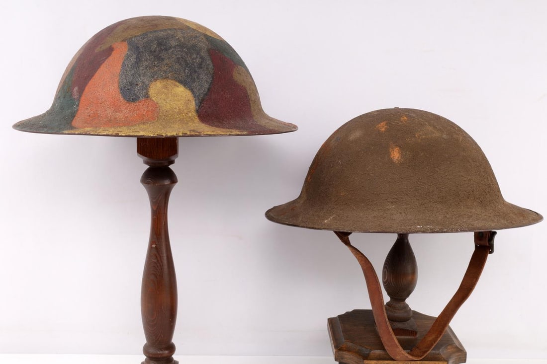 LOT 2 WWI US ARMY M1917 CAMOUFLAGE BRODIE HELMETS: Lot of two (2) WWI United States Army M1917 Brodie helmets WITH their interior liners. One helmet features camouflage painted to exterior. Both helmets interiors feature leather liner with swivel bale