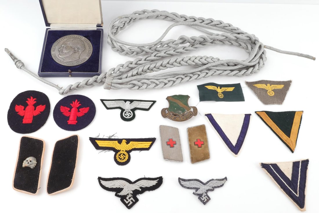 ASSORTED WWII GERMAN PATCH & INSIGNIA LOT: Lot includes a cased WWII German Luftwaffe Goring medallion table award, sword knot/portepee, assortment of German eagles, chevrons, and more. Some wear on the patches are commensurate with age, but l