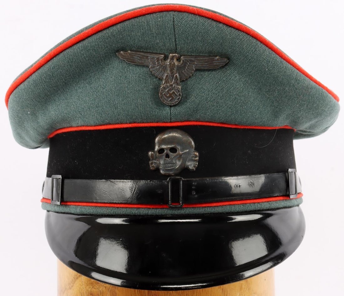 WWII GERMAN SS ARTILLERY OFFICER VISOR: Green/grey visor with silvered brass Parteiadler and totenkopf pins. Pins measure 1 1/8 and 2 5/8 inches. Non-fluorescing. Interior diameter measures 7 3/8 inches. Very good condition.