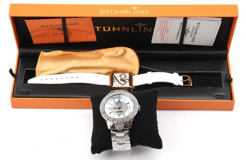 LADIES AND MANS FASHION LOT OF TWO WATCHES: Fashion lot of two name brand watches. To include: a ladies Stuhrling Original two-tone stainless steel watch, heart-shaped Krysterna Crystals embedded in face and white leather 9" band (complete in b