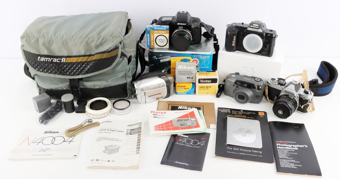ASSORTED CAMERAS & PHOTO EQUIPMENT LOT OF 14: Nikon FM SLR camera. Black and gray camera with instruction manual and woven rope neck strap. Missing secondary hand grip. Very good condition. Nikon N70. Black camera with original box, instruction m