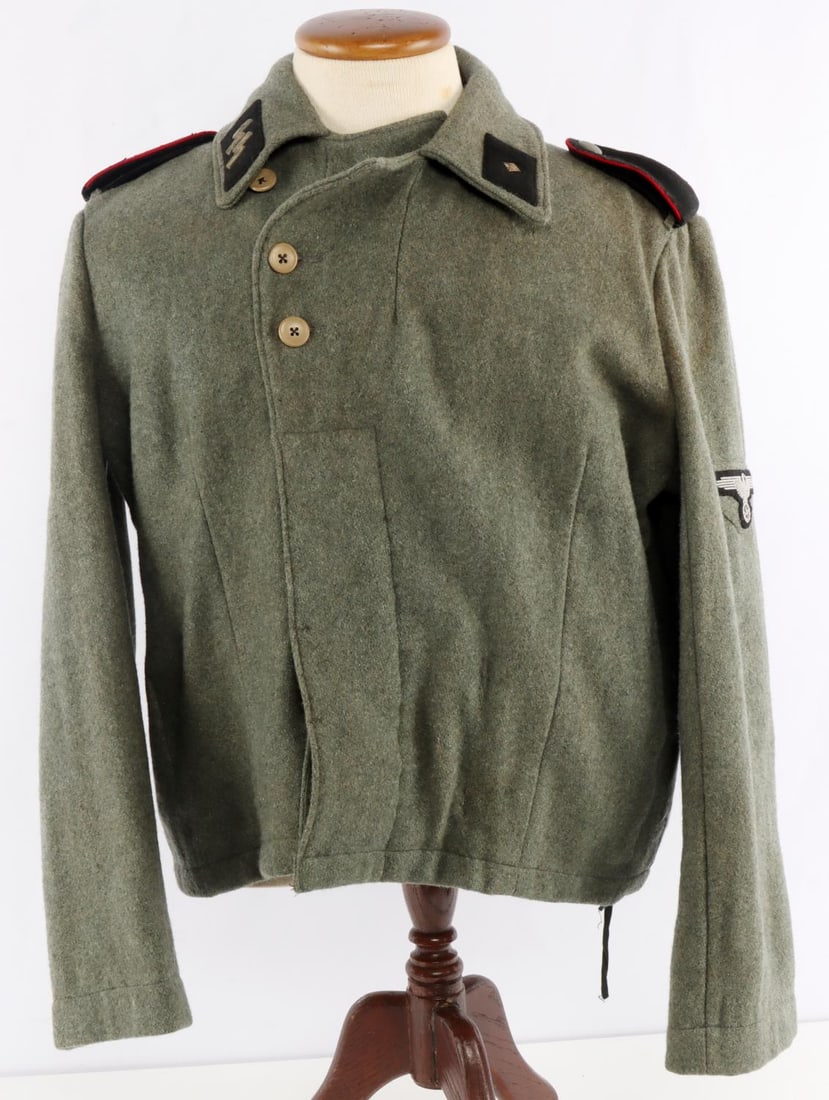 GERMAN WAFFEN SS ARTILLERY ASSAULT GUNNER WRAP: Green artillery wrap with raised SS collar tab, shoulder boards and Parteiadler patch. Very good condition with age wear. No ink stamps on interior. Appears to be an XL wrap. Non-fluorescing.