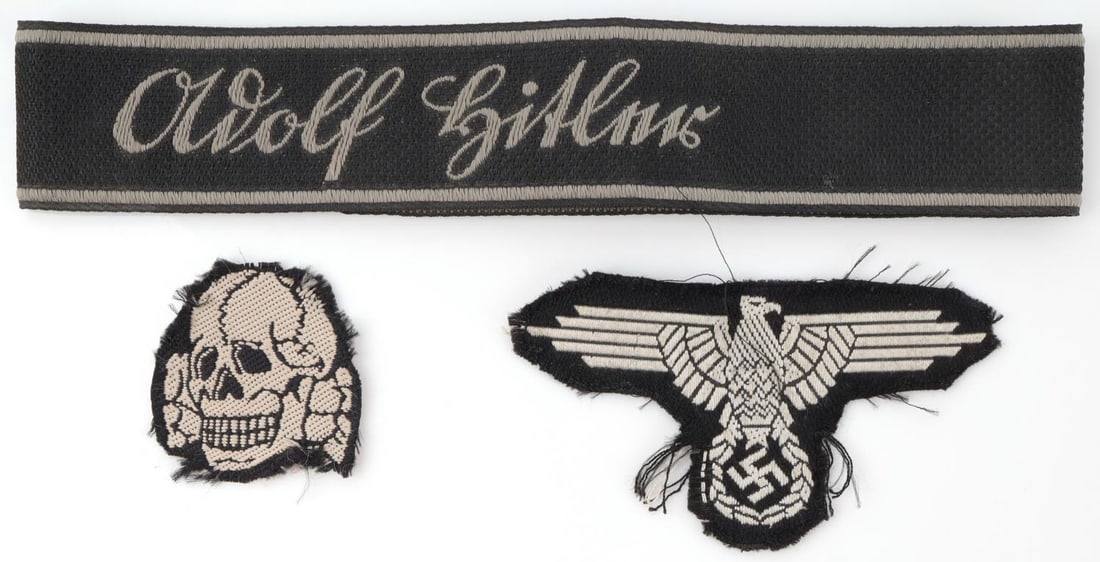 WWII GERMAN THIRD REICH CUFF TITLE & PATCHES: Lot features an Adolf Hitler cuff title, parteiadler patch, and totenkopf patch. Very good condition. Non-fluorescing. Unauthenticated, sold as is.