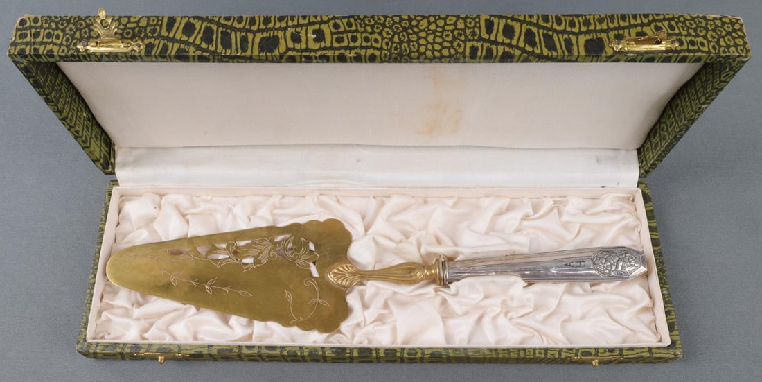 WWII GERMAN THIRD REICH ADOLF HITLER CAKE SERVER: WWII German silver cake server. The handles are adorned with cast floral decorations and marked A. H. for Adolf Hitler. In a simulated alligator hide box. Both are in very good condition. Unauthentica