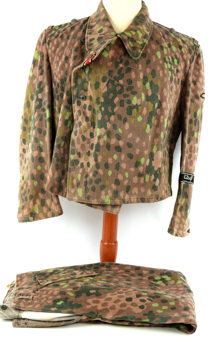 WWII WAFFEN SS PANZER WRAP & TROUSERS 44 DOT HBT: Matching set of Waffen-SS Panzer wrap and trousers in cotton herringbone twill fabric with pea-dot camouflage pattern. Wrap has campaign ribbon in top left buttonhole and, on the left sleeve, a hand-s