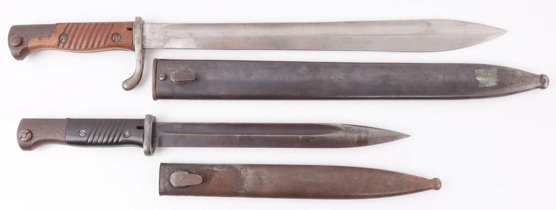 WWI WWIII GERMAN 1898 BUTCHER & MAUSER K98 BAYONET: Lot of two (2) bayonets with scabbards. The first is a Seitengewehr 98/05 with 14.5-inch bright steel blade and wood grips. The ricasso bears maker's mark "Simson & Co., Suhl" and the spine of the bla