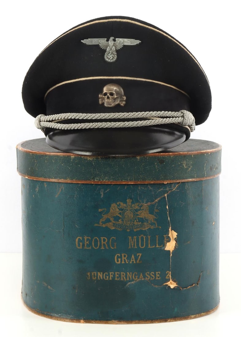 WWII GERMAN THIRD REICH WAFFEN-SS VISOR CAP BOXED: Waffen-SS officer's visor cap. Liner intact. RZM tag in the rear interior behind sweatband. Reichsadler and totenkopf pins on front. Silver bullion braid and white piping on black. Plastic celluloid d
