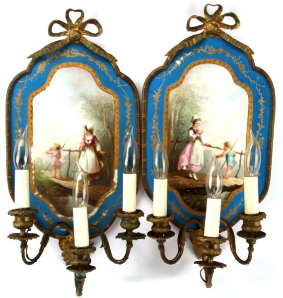 FRENCH PORCELAIN ELECTRIFIED WALL SCONCES PAIR: A fine pair of hand painted Sevres style porcelain and Ormolu scones 17 inches tall and 8 inches wide. The artwork depicts a young woman and a toddler in a landscape scene. The Ormolu frame features t