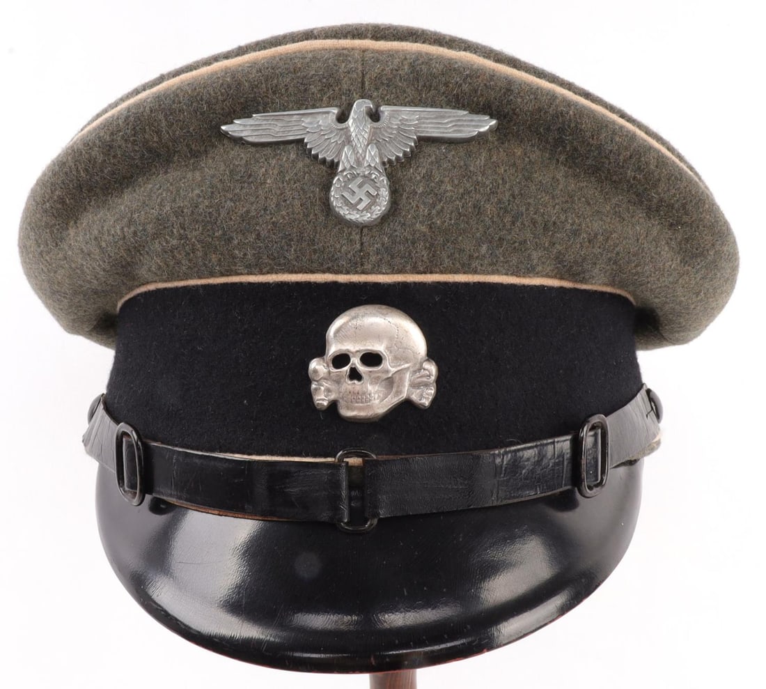 WWII GERMAN THIRD REICH WAFFEN SS NCO VISOR CAP: NCO visor cap for the Waffen-SS. Field gray with white piping and black leather. Reichsadler and totenkopf on front. Interior is gray, with top of cap marked 56 1/2. Approximately a 7 1/8 hat size. Ve
