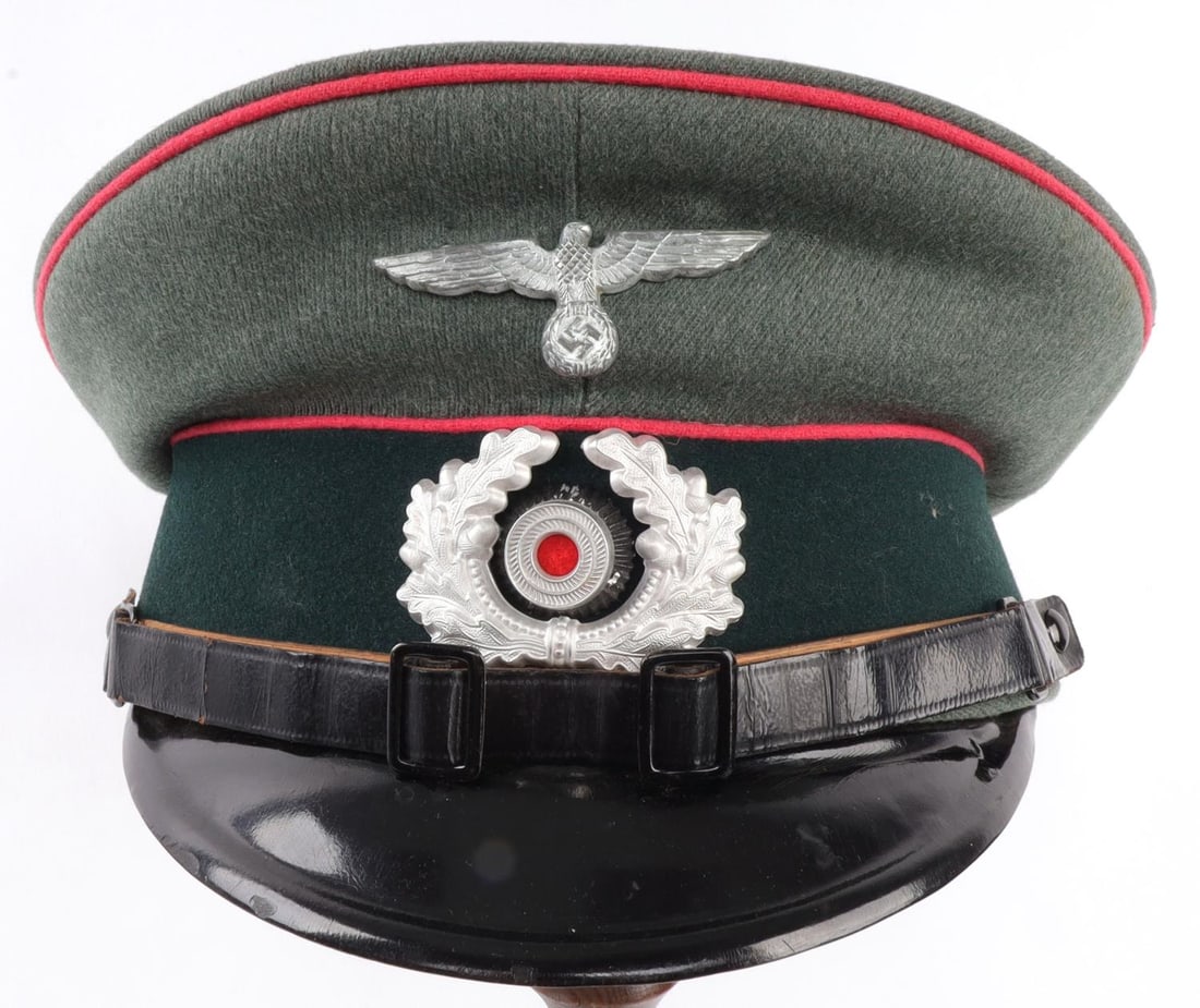 WWII GERMAN THIRD REICH HEER PANZER NCO VISOR CAP: Field gray panzer NCO cap with pink piping and a black leather strap. Reichsadler and Wehrmacht cockade on front. Hat size is marked but smeared into illegibility. Sweat shield has been removed. Dated
