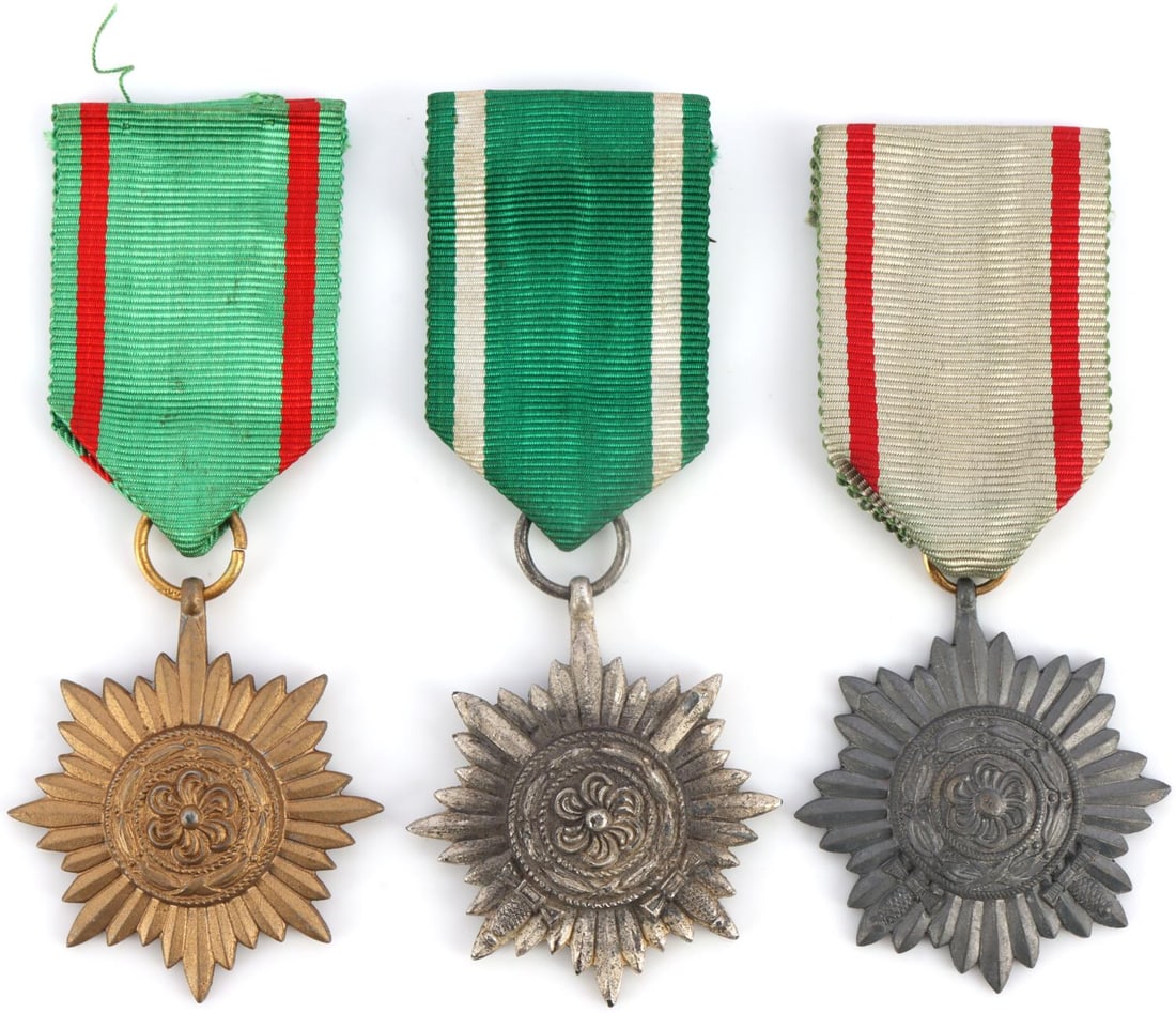 LOT OF 3 WWII THIRD REICH EASTERN PEOPLES MEDALS: Lot of three (3) Eastern People's (Ostvolk) medals in progression of grade. Each medal shows a floral cockade inside a sumnburst. The bronze and the silver each possess crossed swords. 2.6-inch diamet