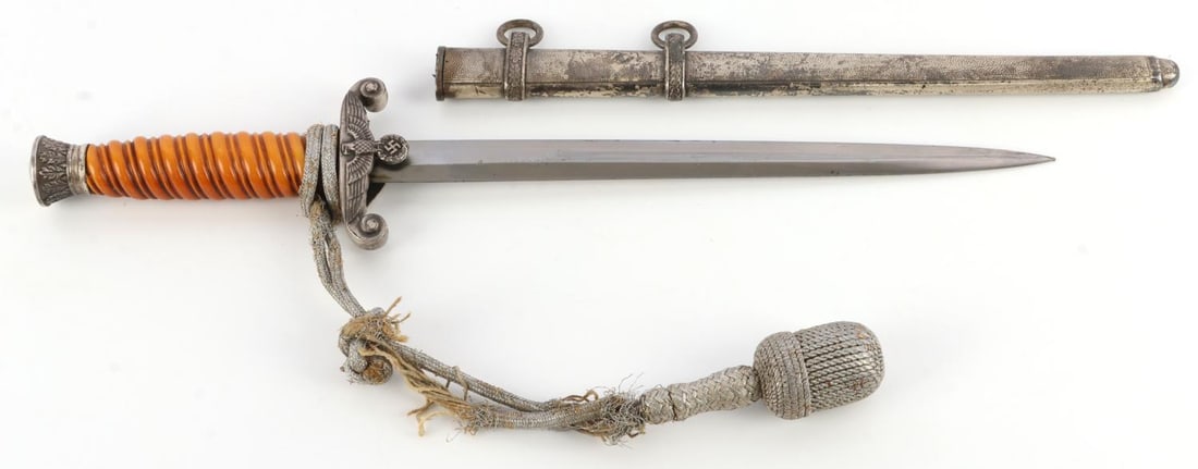 WWII GERMAN THIRD REICH HEER OFFICERS DAGGER: Heer officer's dagger. Orange bakelite grip, oak cluster pommel, and hilt with Reichsadler. Scabbard made of dimpled metal. 10-inch blade, 4.5-inch grip. With non-fluorescing portapee. Portapee rope i
