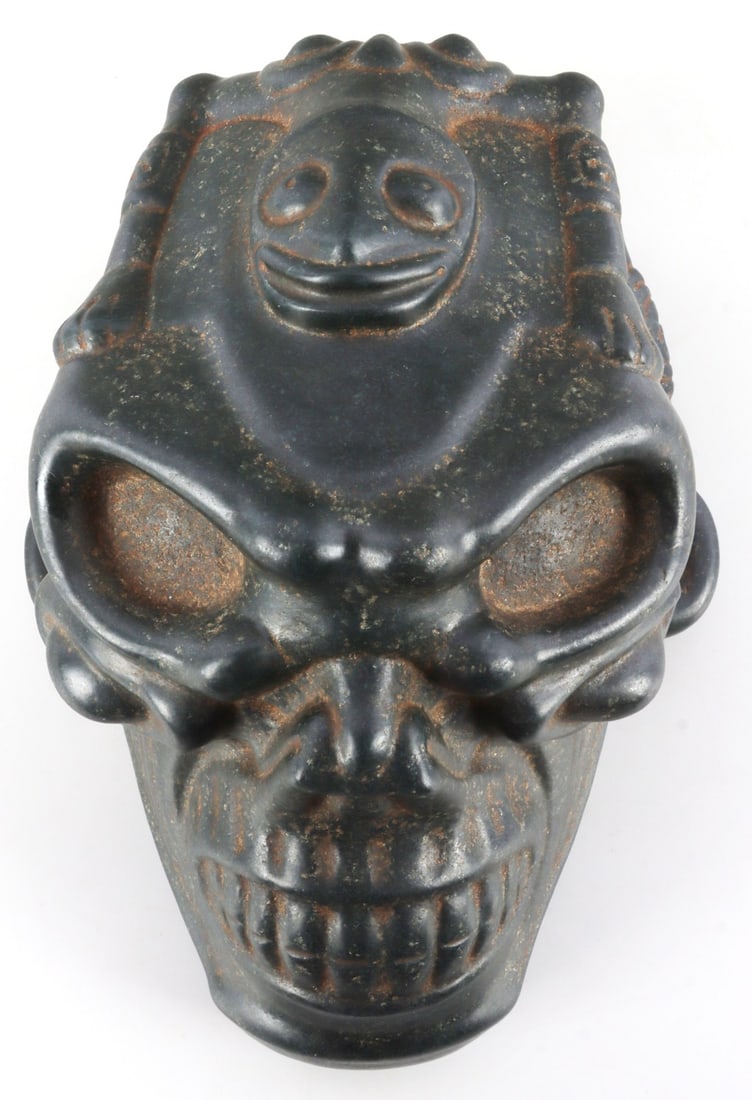 PRECOLUMBIAN TAINO ZOOMORPHIC SKULL: Taino. Pre-Columbian. A superbly sculpted skull with relief carved skeletal Zoomorph on back of cabeza. The head is flat tabular oblique shaped. Large skull like teeth and hollow deep set eyes denote 