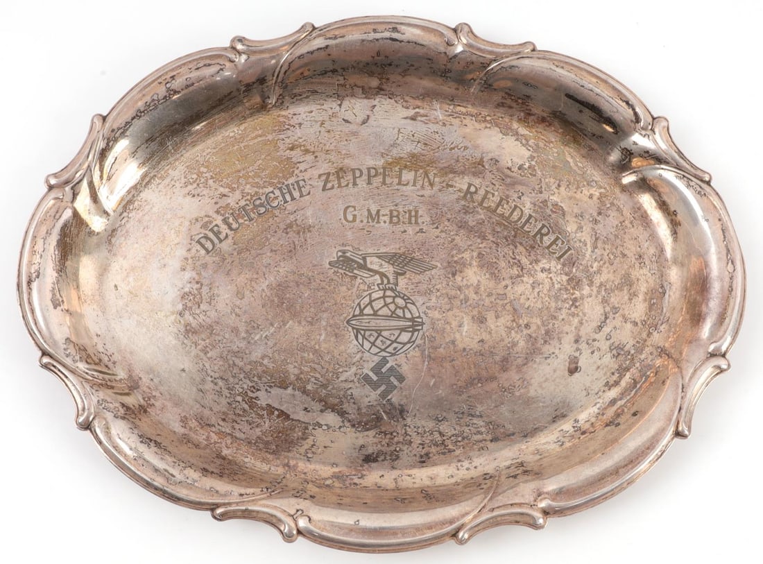 WWII THIRD REICH SILVER SWASTIKA ZEPPELIN PLATTER: Silver platter featuring the image of an eagle grasping the world, with swastika under the globe and zeppelin in front of it. Over the eagle, the platter has the inscription "Deutsche Zeppelin - Reede
