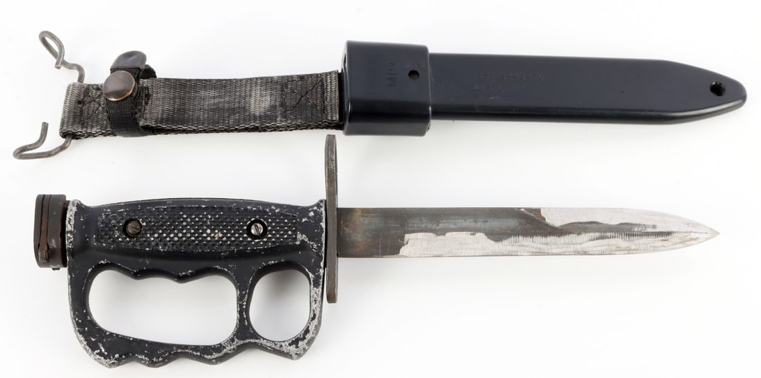 M7 BAYONET W M10 SCABBARD M4 RIFLE KNUCKLE DUSTER: Vietnam-era M7 Bayonet with M10 scabbard M4 rifle with knuckle duster. Maker's mark, "US. M7, GEN CUT." Blade length is 6 1/2 inches. Plastic sheath marked, "M10 ASSY 8448476 MFG 2V376." Very good con