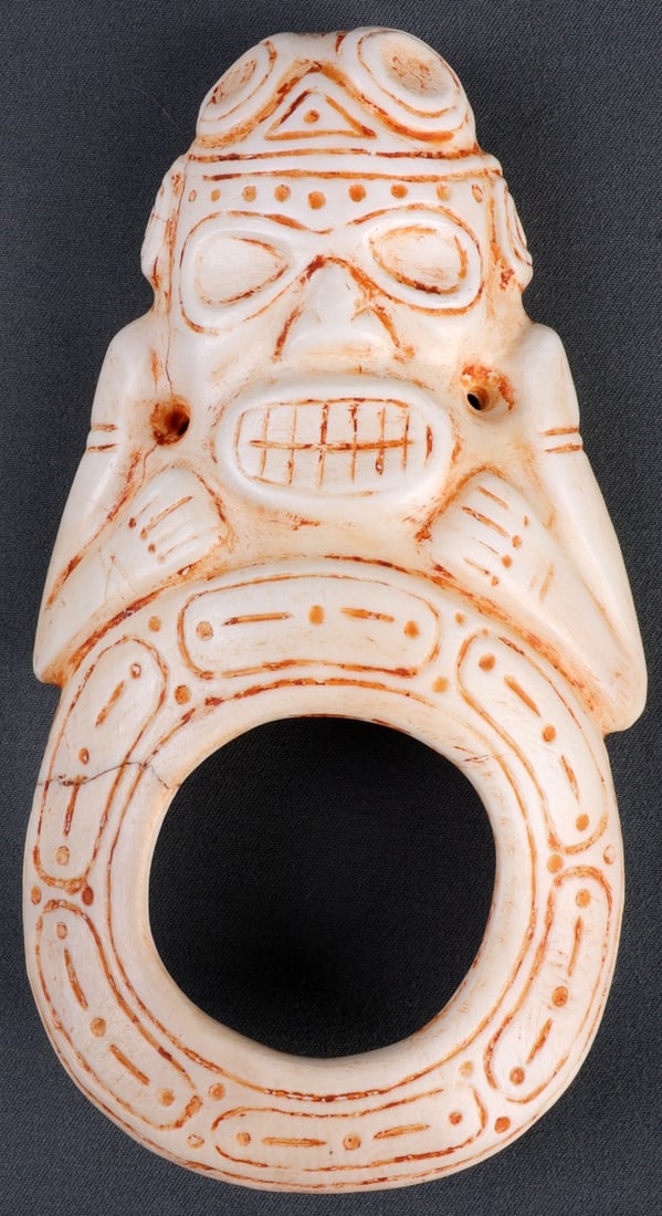 TAINO PRECOLUMBIAN SHELL GUIAZA EFFIGY: Incised shell with figure bearing teeth and holding arms close. Large hole in the center. Two (2) suspension holes on either side. 5 1/4 inches. This lot has a reserve.