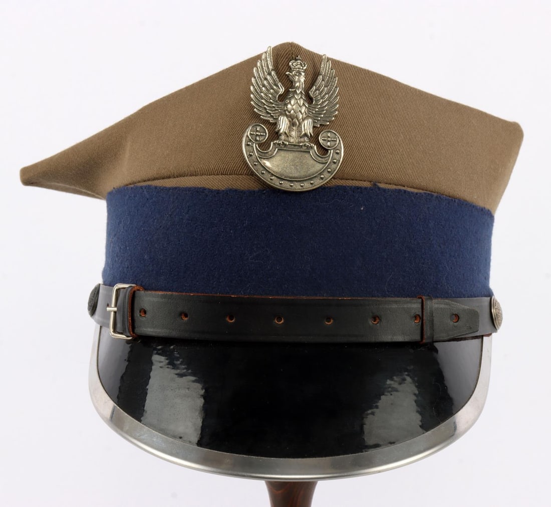 WWII POLISH ROGATYWKA PEAKED FIELD CAP WITH VISOR: Four-peaked czapka of grey gabardine fabric with a navy blue felt band. Crowned eagle insignia and chinstrap buttons bearing the Polish coat of arms. Metal-rimmed visor. Interior has ventilated leathe