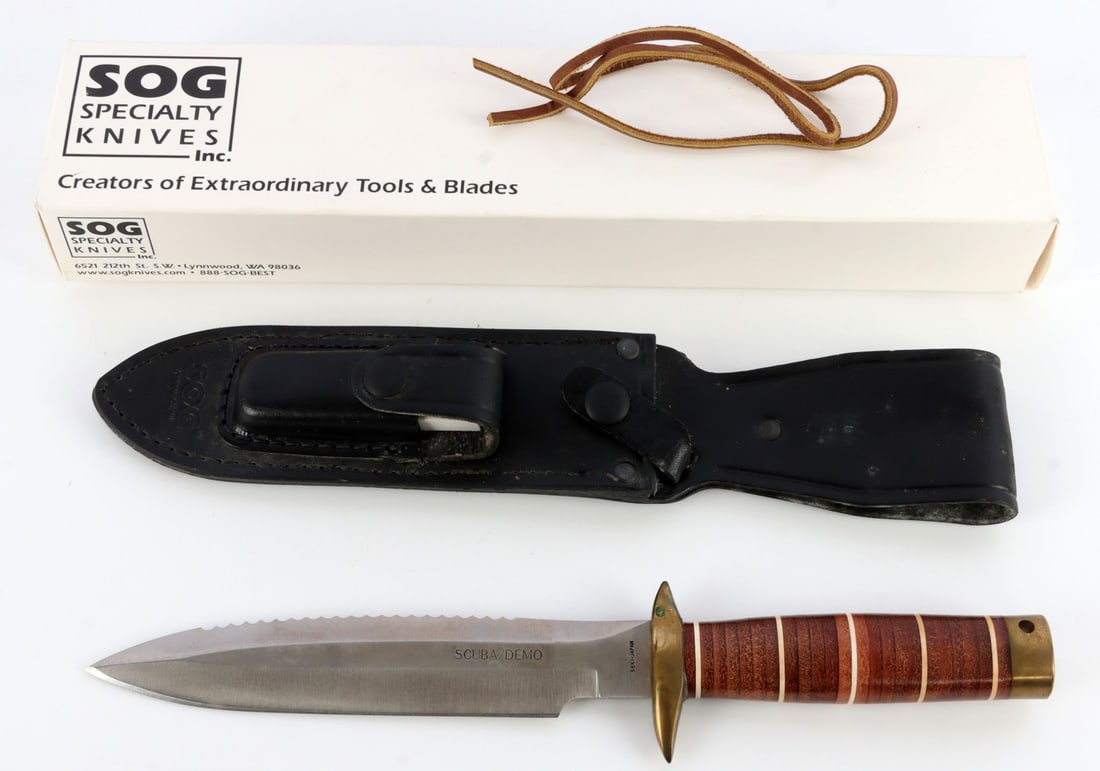 SOG SCUBA DEMO SSD 89 7 1/4 INCH BLADE KNIFE: SOG Scuba/Demo SSD 89, replica of Vietnam-era knife. Blade measures 7 1/4 inches, total length: 12 1/4 inches. Leather handle with brass features. Leather sheath included. In original box, very good c