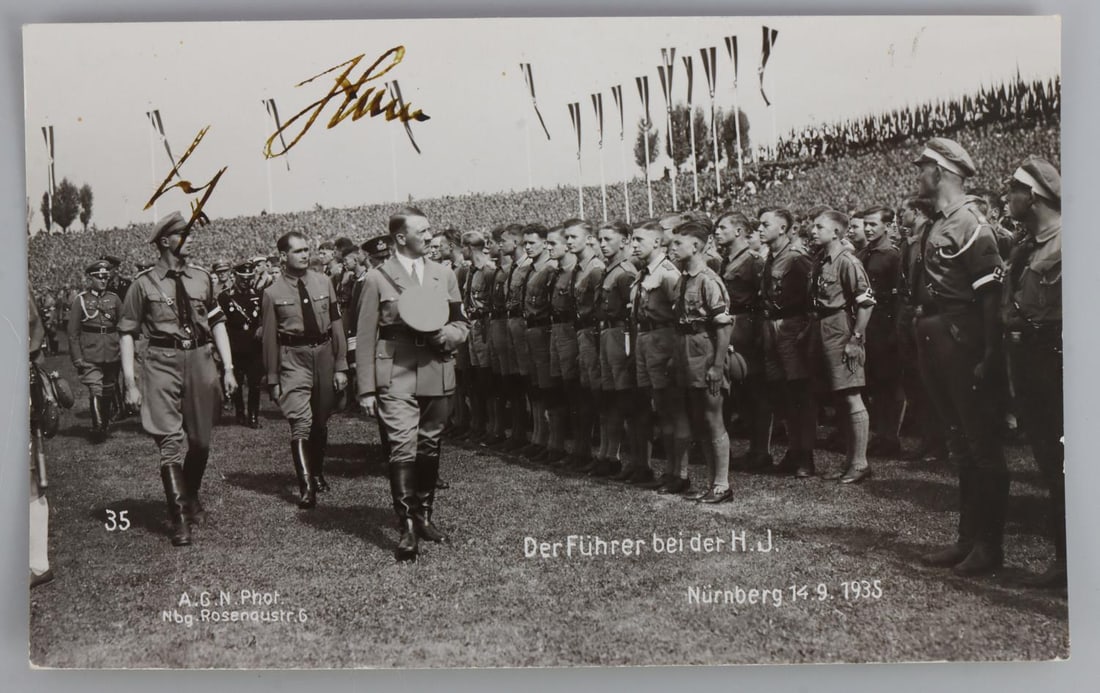 WWII GERMAN REICH ADOLF HITLER SIGNED POSTCARD: Adolf Hitler signed postcard depicts an image of Hitler examining the Hitler Youth. Signature deemed authentic according to standards. Very good, original condition.