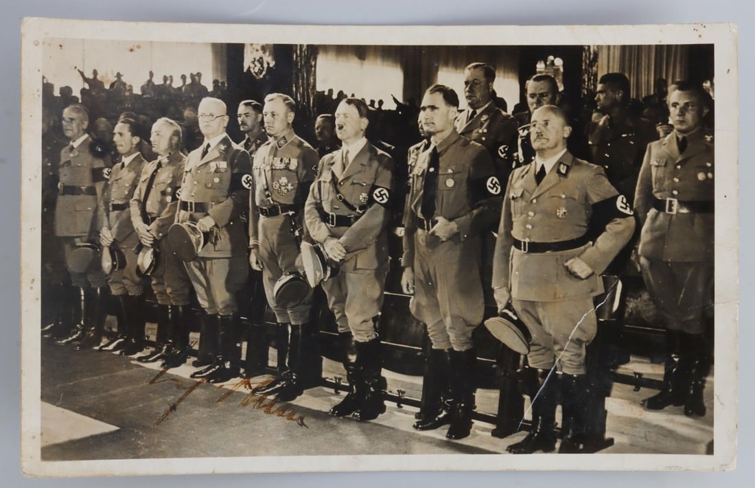 WWII GERMAN REICH ADOLF HITLER SIGNED POSTCARD: Postcard from the Third Reich showing NSDAP leadership, notably Hitler, Goebbels, Streicher, and Hess, at the Nuremberg Rally. Bears the lightning bolt signature of Adolf Hitler. Deemed authentic acco