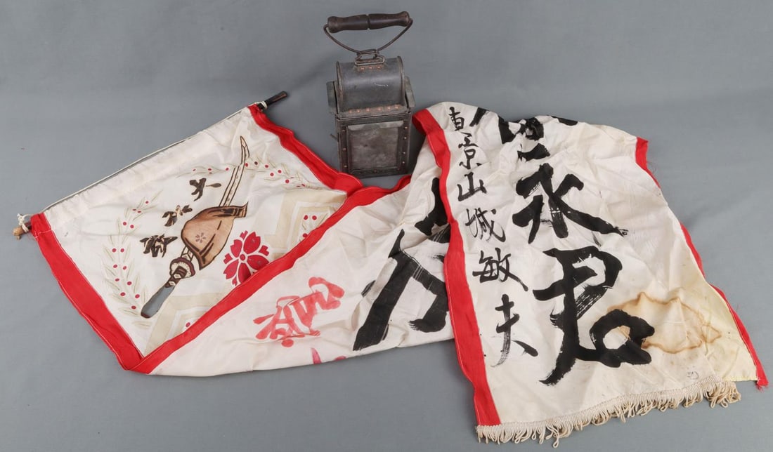WWII GERMAN LANTERN & JAPANESE 99 HELMET PENNANT: Reverse of lantern is stamped S.S. 1938, appears unused, or has a new wick. Pennant is 16 X 54 inches, upper characters and sword grip are missing. Items are in good, overall condition.