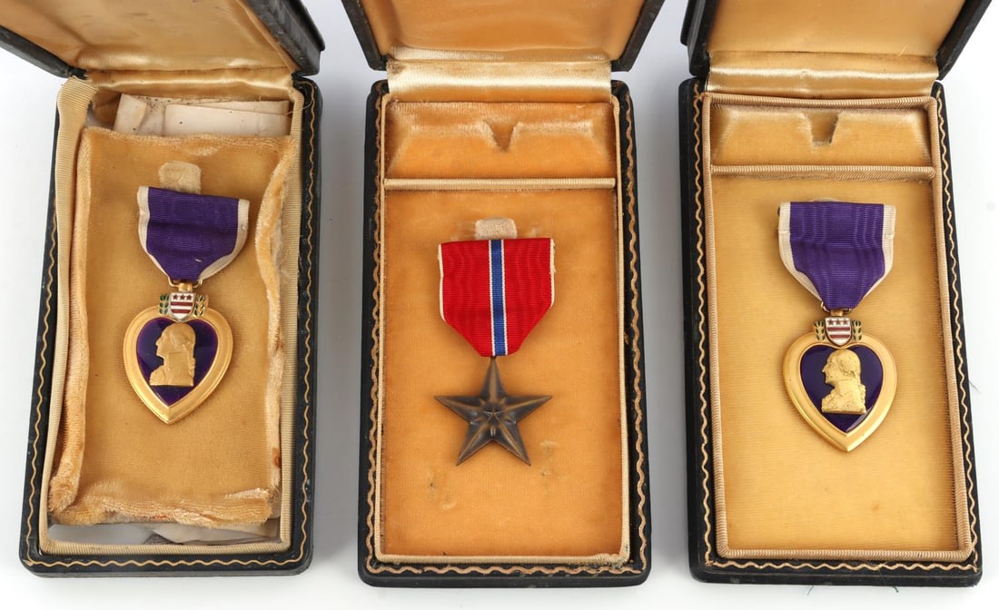 1 WWII NAME BRONZE STAR & 2 CASED PURPLE HEART LOT: Lot of THREE (3) WWII cased award medals. Includes one (1) Bronze Star medal with case labeled "Captain Arch P. Cooper" and two (2) cased Purple Heart medals. Good condition. One case has lost its bac