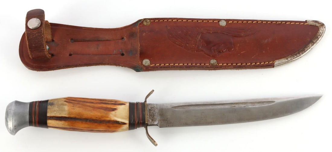 ANTLER HANDLED GERMAN STAG KNIFE FROM UNSCO: Stag antler handled knife from Unsco. Stamped UNSCO SOLINGEN. Knife has seen use and there is some oxidization on copper parts. Leather sheath has the profile of a Native American. 6-inch blade. Very 