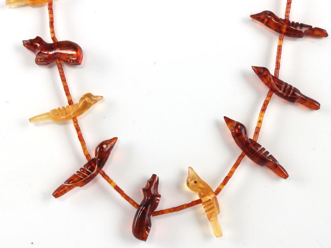 AMBER ZUNI FETISH NECKLACE BY LAVINA TSIKEWA: Hand-carved Zuni fetish necklace made from amber. Various animals are depicted: 20 birds, 1 frog, 1 squirrel, 3 bears, 1 fox, and 1 cat. 34-inch necklace. Hand made silver cones and snap. Attributed t