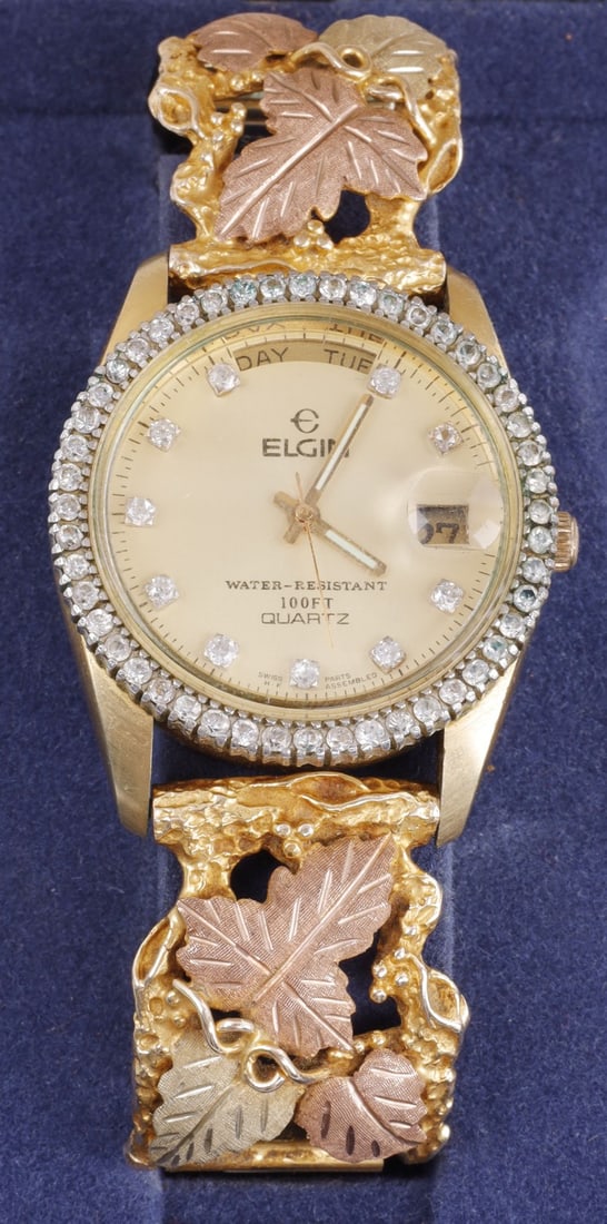 10K BLACK FOREST GOLD WATCH FROM ELGIN: Black forest gold watch. Leaves on side are black forest and 10K. Band is 10K. Marked 10K on the back. 7-inch band. Diameter of face is 1.25 inches. Weighs 76.2 grams. Includes box. This lot has a res