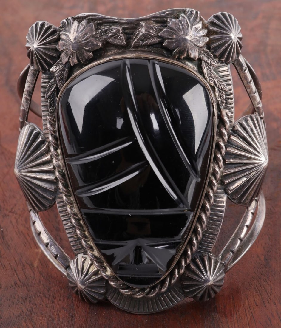 STERLING SILVER BLACK ONYX MAYAN CUFF BRACELET: Hand-made sterling silver cuff bracelet with Mayan face design carved in black onyx. 20th century. Floral details surrounding stone. Stamped "sterling." 70.7 grams gross weight. Interior measures 6 in