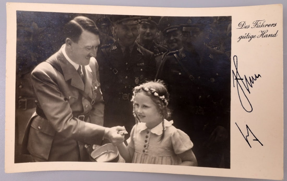 WWII GERMAN THIRD REICH ADOLF HITLER SIGNATURE: Postcard with Heinrich Hoffmann photograph as its central element, showing Adolf Hitler with Bernile Nienau. Picture is labeled "Das Fuhrers gutige Hand" (The Fuhrer's Guiding Hand." The photograph be